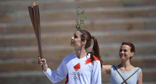 An athlete holds the Olympic torch during the olympic flame handover ceremony for the 2020 Tokyo Summer Olympics, on March 19, 2020 in Athens. ARIS MESSINIS / AFP / POOL
