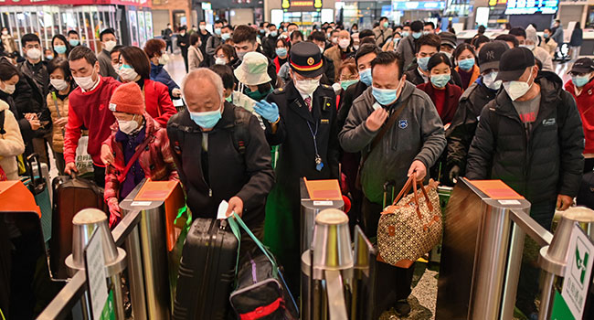 People wearing face masks as a preventive measure against the COVID-19 novel coronavirus walk to a train, one of the stops being Wuhan, at a station in Shanghai on March 28, 2020.