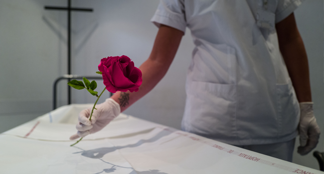 A mortuary service agent puts a plastic flower on a stretcher at the Emile Muller hospital morgue on April 22, 2020, in Mulhouse, eastern France, on the 37th day of a lockdown aimed at curbing the spread of the COVID-19 pandemic, caused by the novel coronavirus. SEBASTIEN BOZON / AFP