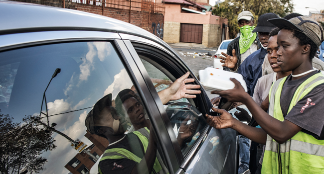 Homeless men approach a car from where a Muslim man offers "zakat", or alms, given to poor people during Ramadan, in Fordsburg, Johannesburg, on April 23, 2020. MARCO LONGARI / AFP