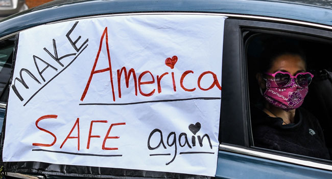 A demonstrator shows a sign with "Make America safe again" written on it while driving past the Governor's Mansion during a drive by protest in Atlanta, Georgia on April 24, 2020. CHANDAN KHANNA / AFP