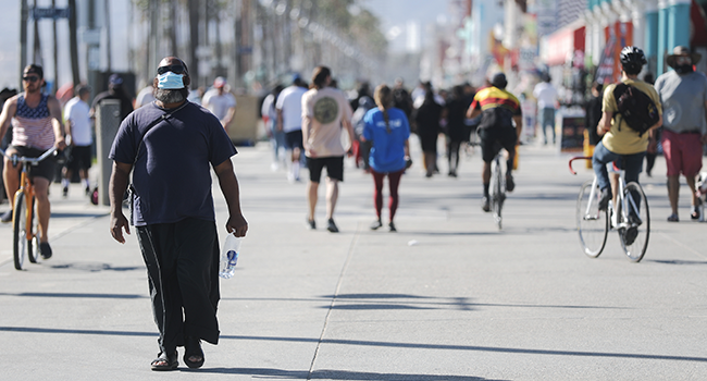 A man wears a face mask along the Venice Beach boardwalk on the day Los Angeles County reopened its beaches, which had been closed due the coronavirus pandemic, on May 13, 2020 in Venice, California.