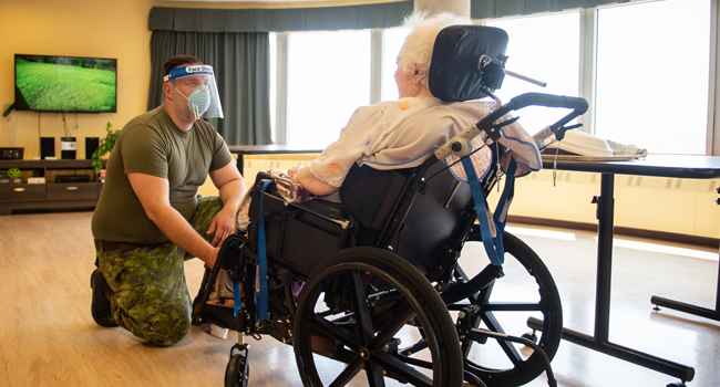 In this image obtained from Canadian Armed Forces Combat Camera, a Canadian soldier aids a senior citizen on May 10, 2020, at the Vigi Queen Elizabeth Residential and Long-Term Care Centre in Montreal, Quebec. Genevieve Beaulieu / Canadian Armed Forces / AFP