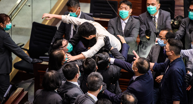 Pro-democracy lawmaker Ted Hui (C) is carried out by security during a scuffle with pro-Beijing lawmakers at the House Committee's election of chairpersons at the Legislative Council in Hong Kong on May 18, 2020. Anthony WALLACE / AFP