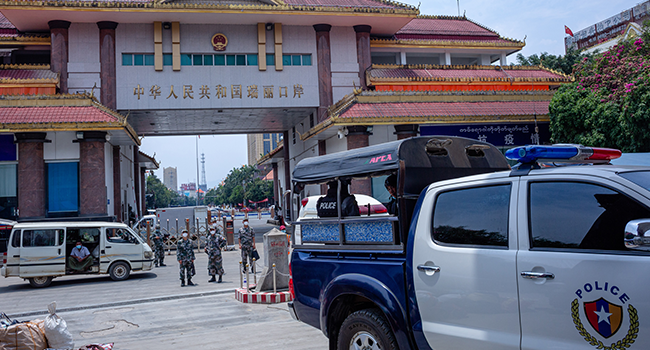 Chinese border police guards keep watch as migrant workers return from China at the Myanmar border gate in Muse in Shan state on May 12, 2020. Phyo Maung Maung / AFP
