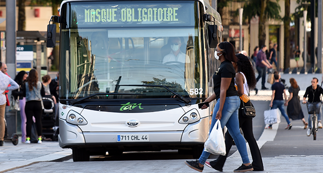 Women wearing a protective face mask walk past a bus with the display reading 'Mask is compulsory', in Nantes, western France, on May 16, 2020, after the country eased lockdown measures taken to curb the spread of the COVID-19 pandemic, caused by the novel coronavirus, on May 11. JEAN-FRANCOIS MONIER / AFP