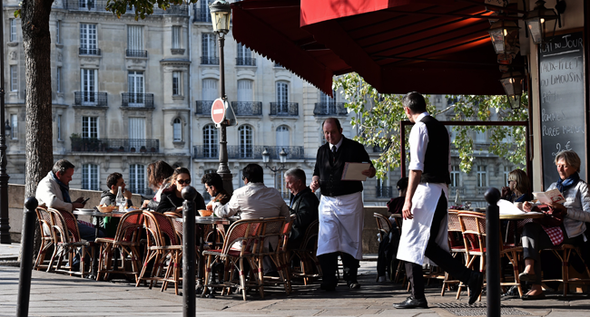 In this file photo taken on October 11, 2016 People have lunch at the terrasse of a restaurant in Paris. Bars and restaurants will reopen progressively in France from June 2, as the country enters phase 2 of its novel coronavirus' (COVID-19) lockdown easing. CHRISTOPHE ARCHAMBAULT / AFP