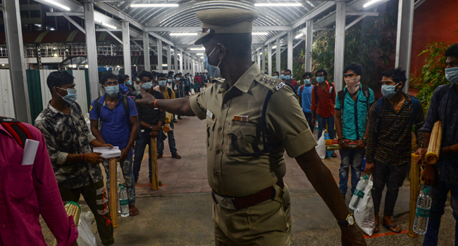 A security personnel (C) directs stranded migrant labourers queueing to board a special train to Odisha from MGR Central railway station after the government eased a nationwide lockdown imposed as a preventive measure against the COVID-19 coronavirus, in Chennai on May 9, 2020. Arun SANKAR / AFP