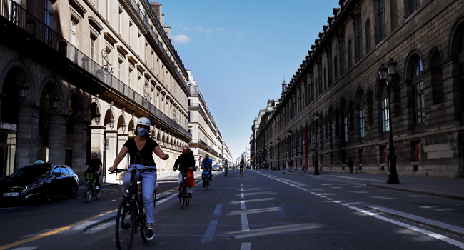 People cycle with their bike down the Rue de Rivoli, by the Louvre museum, in Paris on May 19, 2020 as France eases lockdown measures taken to curb the spread of the COVID-19 (the novel coronavirus). THOMAS COEX / AFP