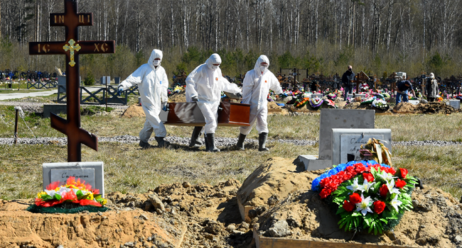 Cemetery workers wearing protective gear bury a coronavirus victim at a cemetery on the outskirts of Saint Petersburg on May 6, 2020. OLGA MALTSEVA / AFP