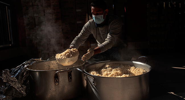 A kitchen worker prepares hot meals at Thava Indian restaurant, at The Gardens, for the daily food distribution in an informal settlement in Tembisa, Johannesburg, on April 24, 2020. Luca Sola / AFP