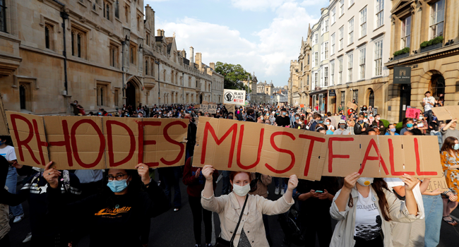 Demonstrators hold placards during a protest arranged by the 'Rhodes Must Fall' campaign, calling for the removal of a statue of British businessman and imperialist Cecil John Rhodes, from outside Oriel College at the University of Oxford in Oxford, west of London on June 9, 2020. Adrian DENNIS / AFP