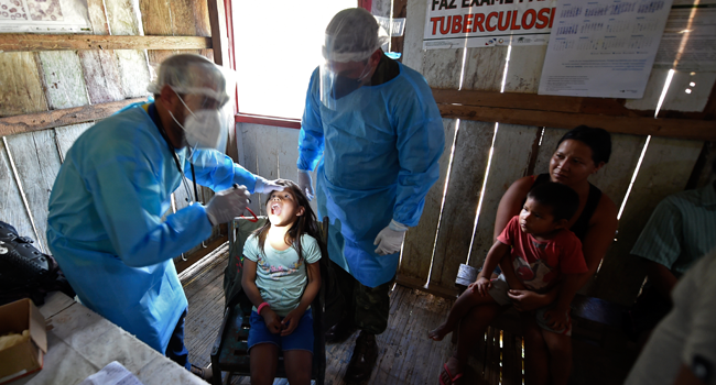 Doctors of the Brazilian Armed Forces check an indigenous child of the Mayoruna ethnic group, in the Cruzeirinho village, near Palmeiras do Javari, Amazonas state, northern Brazil, on June 18, 2020, amid the COVID-19 pandemic. EVARISTO SA / AFP