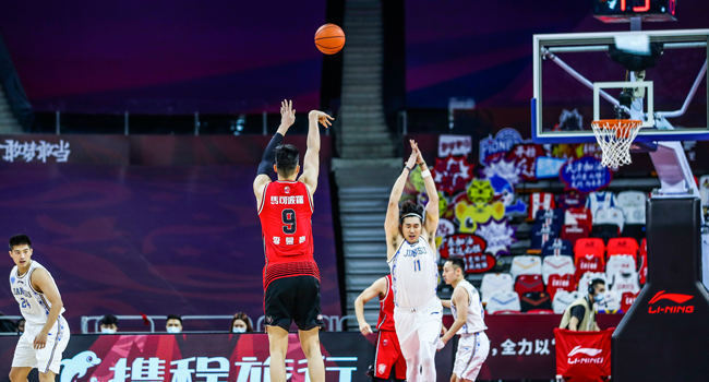 Li Muhao (C in red) of Shenzhen Aviators takes a shot during the CBA basketball match between Suzhou Dragons and Shenzhen Aviators in Dongguan in China's southern Guangdong province on June 20, 2020. STR / AFP