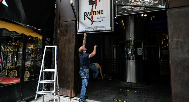 Employees remove movie posters outside The Max Linder Cinema Theatre in Paris on June 18, 2020, ahead of the re-opening of cinema halls and theatres, as France eases lockdown measures taken to curb the spread of the Covid-19 pandemic (novel coronavirus). STEPHANE DE SAKUTIN / AFP