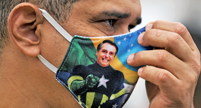 A supporter of President Jair Bolsonaro wears a face mask with Bolsonaro's image during a demonstration at Copacabana beach in Rio de Janeiro, Brazil, on June 7, 2020. CARL DE SOUZA / AFP