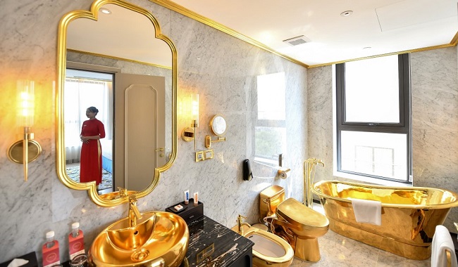 A staff member poses for a photograph inside the 1,000 USD per night executive two bedroom suite of the newly-inaugurated Dolce Hanoi Golden Lake hotel, the world's first gold-plated hotel, in Hanoi on July 2, 2020. (Photo by Manan VATSYAYANA / AFP)