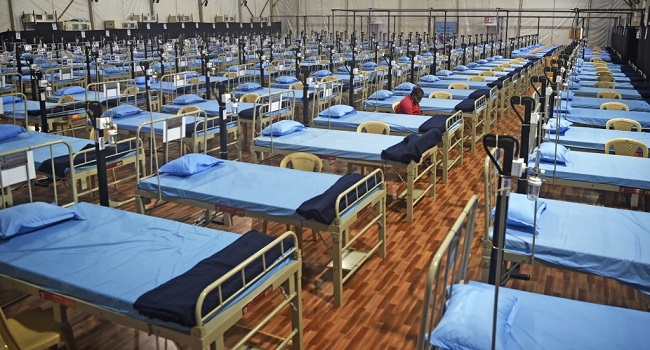 A man sits next to beds at a newly built hospital to treat Covid-19 coronavirus patients at the Mahalaxmi Racecourse, in Mumbai on July 7, 2020. - India on July 6 became the country with the third-highest coronavirus caseload in the world, as a group of scientists said there was now overwhelming evidence that the disease can be airborne -- and for far longer than originally thought. India's major cities including New Delhi and Mumbai are suffering the most, and critics say not enough tests are being conducted -- meaning that many COVID-19 infections are likely to go undiagnosed. (Photo by Punit PARANJPE / AFP)