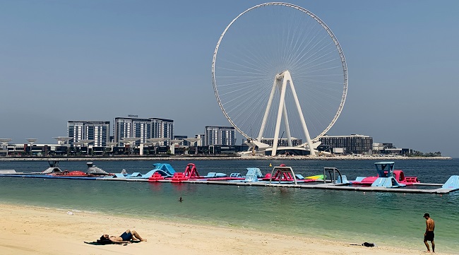 A man sunbathes along the Marina beach near the Ain Dubai Ferris wheel in the Gulf emirate of Dubai on July 7, 2020. (Photo by Giuseppe CACACE / AFP)