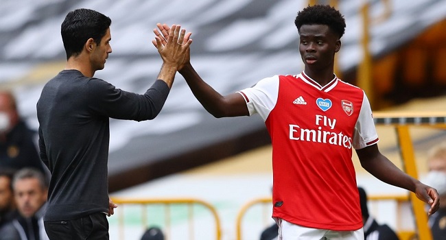 Arsenal's Spanish head coach Mikel Arteta (L) high-fives Arsenal's English striker Bukayo Saka (R) as Saka goes off substituted during the English Premier League football match between Wolverhampton Wanderers and Arsenal at the Molineux stadium in Wolverhampton, central England on July 4, 2020. (Photo by Michael Steele / POOL / AFP)