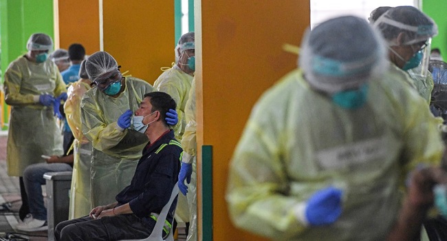 (FILES) In this file photo taken on June 10, 2020, health workers takes nasal swab test samples from essential workers to detect the COVID-19 novel coronavirus before the workers return to work in Singapore. - Singapore plunged into recession in the second quarter as growth fell 41.2 percent quarter-on-quarter with the trade-dependent economy hammered by the coronavirus, preliminary data showed on July 14. (Photo by Roslan RAHMAN / AFP)