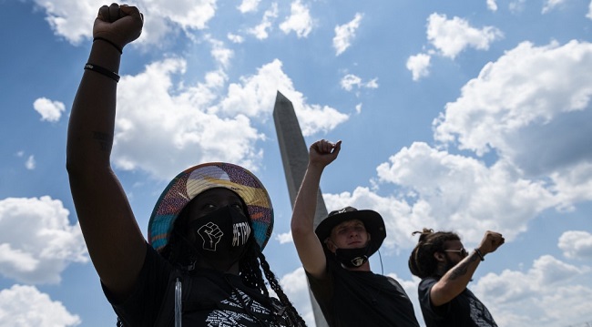 Protesters raise their fists during a small rally against racism in the US next to the Washington Memorial in Washington, DC, on July 4, 2020, ahead of the Independence Day celebrations. - Wide spread national protests over police brutality and systemic racism have taken place following the police killing of George Floyd in Minneapolis in May. (Photo by ROBERTO SCHMIDT / AFP)
