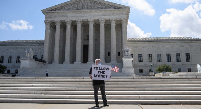 A man holds a sign in front of the US Supreme Court in Washington, DC, on July 9, 2020. - The court ruled that US President Donald Trump must hand over financial records to prosecutors in New York. In a 7-2 ruling, the court said the president does not have absolute immunity from criminal investigation. (Photo by NICHOLAS KAMM / AFP)