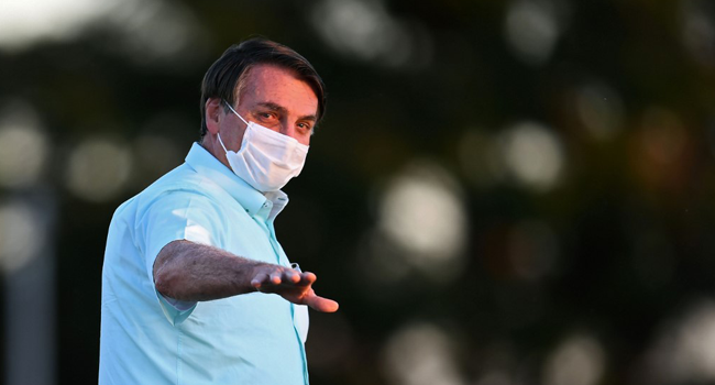 Brazilian President Jair Bolsonaro (C) walks towards supporters in the garden of the Alvorada Palace in Brasilia, on July 22, 2020. EVARISTO SA / AFP