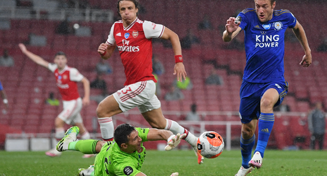 Arsenal's Argentinian goalkeeper Emiliano Martinez (C) dives to block a shot from Leicester City's English striker Jamie Vardy (R) during the English Premier League football match between Arsenal and Leicester City at the Emirates Stadium in London on July 7, 2020. Michael Regan / POOL / AFP