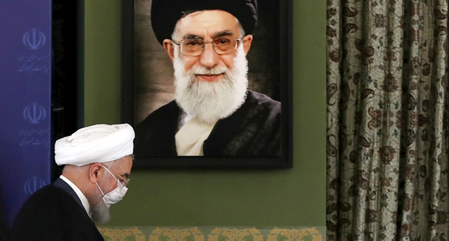 A handout picture provided by the Iranian Presidency on July 18, 2020, shows President Hassan Rouhani walking past a portrait of Iran's Supreme Leader Ayatollah Ali Khamenei. Iranian Presidency / AFP