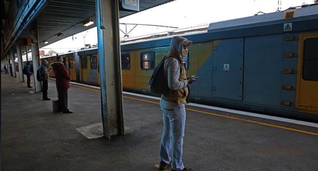 Commuters wearing face masks wait on a platform to board a train at Pretoria Station as the Passenger Rail Agency of South Africa (PRASA) resumes its operations on July 1, 2020. Phill Magakoe / AFP