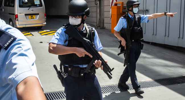 Armed police officers escort a van (behind) transporting Tong Ying-kit (not pictured) who is accused of deliberately driving his motorcycle into a group of police officers on July 1, as he arrives at West Kowloon court in Hong Kong on July 6, 2020. ISAAC LAWRENCE / AFP