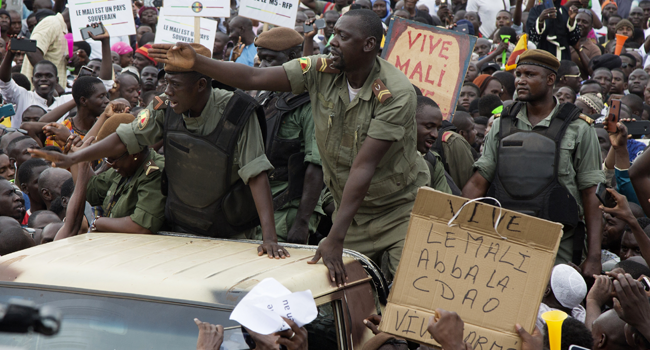 Demonstrators gather around a group of Malian soldiers during a protest to support the Malian army and the National Committee for the Salvation of the People (CNSP) at the Independence square in Bamako, on August 21, 2020, 3 days after the military overthrow of the President. ANNIE RISEMBERG / AFP