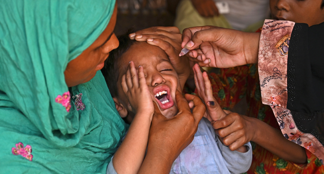 A health worker administers polio vaccine drops to a child during a polio vaccination door-to-door campaign in Lahore on August 16, 2020. Arif ALI / AFP