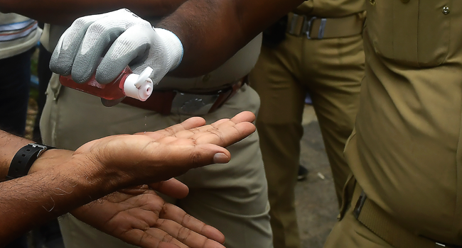 Police officials use hand sanitiser after stopping Activists of Congress Party trying to break police barricades in front of the Raj Bhavan (Governor's House) during a protest against the Bharatiya Janata Party (BJP) led central government and state Governors, in Kolkata on July 27, 2020. Dibyangshu SARKAR / AFP
