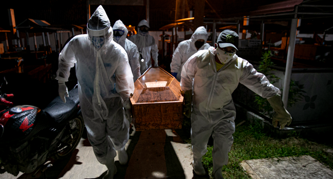 In this file photo taken on May 30, 2020 gravediggers wearing protective clothing carry the coffin of a victim of the novel coronavirus COVID-19 for its burial at the Recanto da Paz Municipal Cemetery in the city of Breves, southwest of Marajo Island, an island at the mouth of the Amazon River in the Brazilian state of Para,Brazil. Tarso SARRAF / AFP