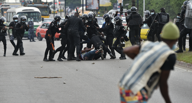 Policemen beat a demonstrator during a rally of former Ivory Coast President Laurent Gbagbo's supporters to protest against his absence on the presidential candidates electoral list, near the electoral commission headquarters on boulevard Latrille in Cocody district of Abidjan on August 6, 2020.  SIA KAMBOU / AFP