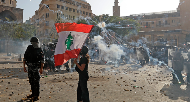 A Lebanese protester waves the national flag during clashes with security forces in downtown Beirut on August 8, 2020, following a demonstration against a political leadership they blame for a monster explosion that killed more than 150 people and disfigured the capital Beirut. JOSEPH EID / AFP