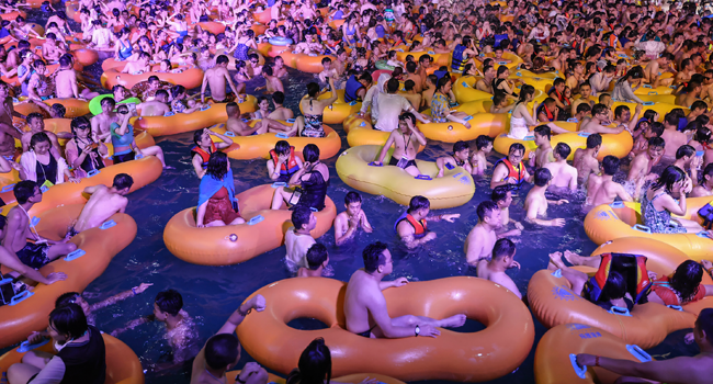 This file photo taken on August 15, 2020 shows people watching a performance as they cool off in a swimming pool in Wuhan in China's central Hubei province. STR / AFP
