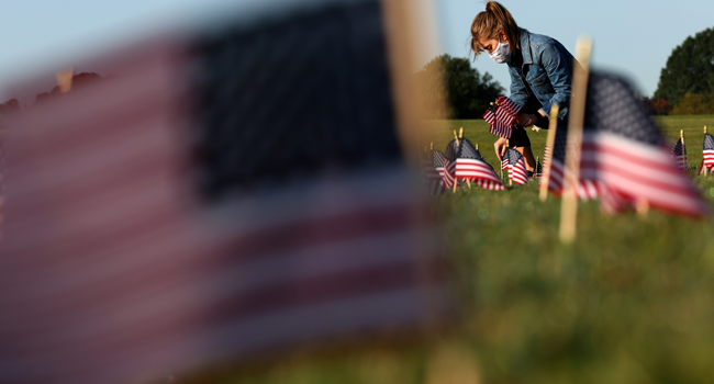  Carmen Wilke places flags at a COVID Memorial Project install of 20,000 American flags on the National Mall as the United States crosses the 200,000 lives lost in the COVID-19 pandemic September 22, 2020 in Washington, DC. Win McNamee/Getty Images/AFP