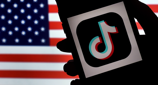  In this file photo illustration taken on August 03, 2020, the social media application logo, TikTok is displayed on the screen of an iPhone on an US flag as the background in Arlington, Virginia. Olivier DOULIERY / AFP