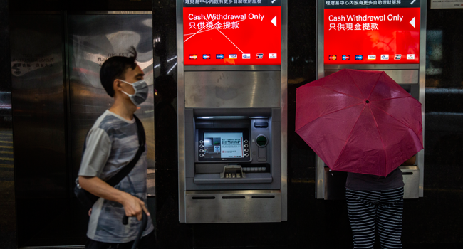 A women (R) uses a HSBC automated teller machine (ATM) in Hong Kong on September 21, 2020. ISAAC LAWRENCE / AFP