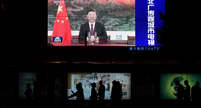 An image of Chinese President Xi Jinping appearing by video link at the United Nations 75th anniversary is seen on an outdoor screen as pedestrians walk past below in Beijing on September 22, 2020. GREG BAKER / AFP