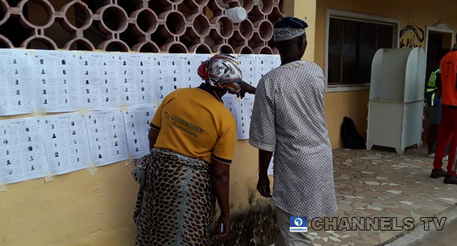 Voters in Ondo state inspect a notice board at a polling unit.