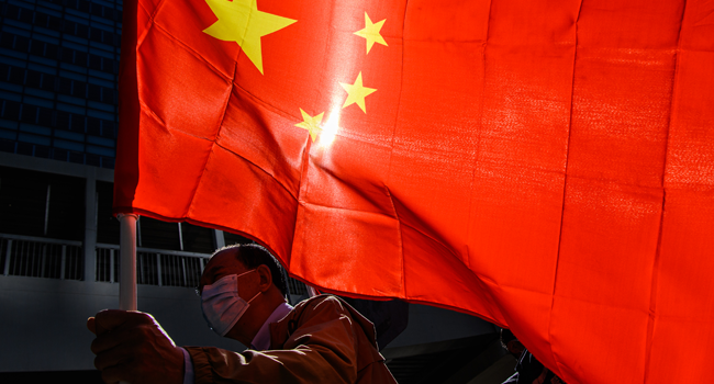 A pro-Beijing supporter holds China's national flag as he and others gather outside the Legislative Council in Hong Kong on November 12, 2020, a day after the city's pro-Beijing authorities ousted four pro-democracy lawmakers. Anthony WALLACE / AFP