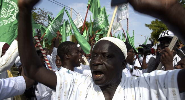 Men gesture and hold flags during a protest against French President at the Place de l'obelisque, in Dakar, on November 7, 2020. Seyllou / AFP