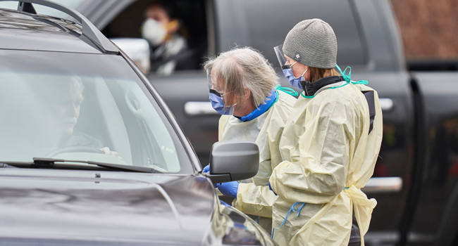  In this file photo taken on March 17, 2020 health care workers speak with patients at a drive-thru Covid-19 assessment center in London, Ontario.  Geoff Robins / AFP