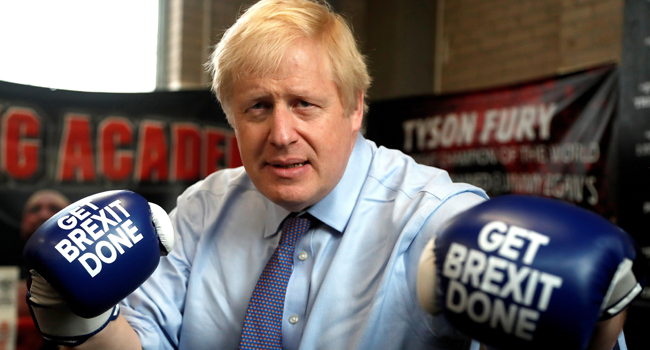 In this file photo taken on November 19, 2019 Britain's Prime Minister and leader of the Conservative Party, Boris Johnson wears boxing gloves emblazoned with "Get Brexit Done" as he poses for a photograph at Jimmy Egan's Boxing Academy in Manchester north-west England on November 19, 2019, during a general election campaign trip. Frank Augstein / POOL / AFP