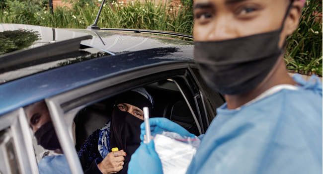 A woman sits in her car before receiving a COVID-19 swab test by a Lab Technician from the Mullah Laboratories at the Flower Hall parking, at Wits University, Braamfontein, Johannesburg, during a drive through COVID-19 swab test campaign, on January 5, 2021. Luca Sola / AFP