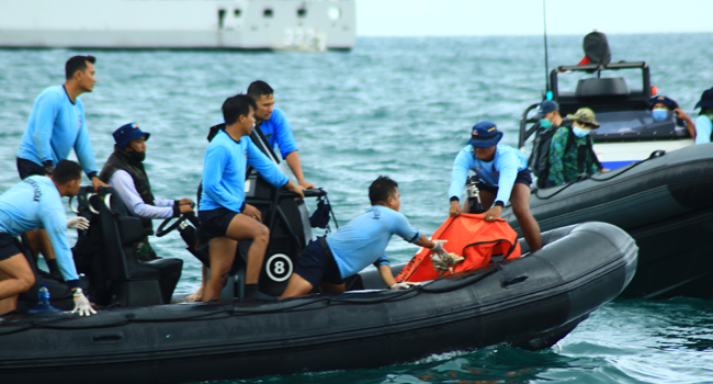 Navy divers bring back bags of debris they collected to the search and rescue ship off the northern coast of Jakarta on January 12, 2021, during recovery operations for Sriwijaya Air flight SJ182 which crashed shortly after takeoff from Jakarta on January 9 with 62 people onboard. Azwar Ipank / AFP